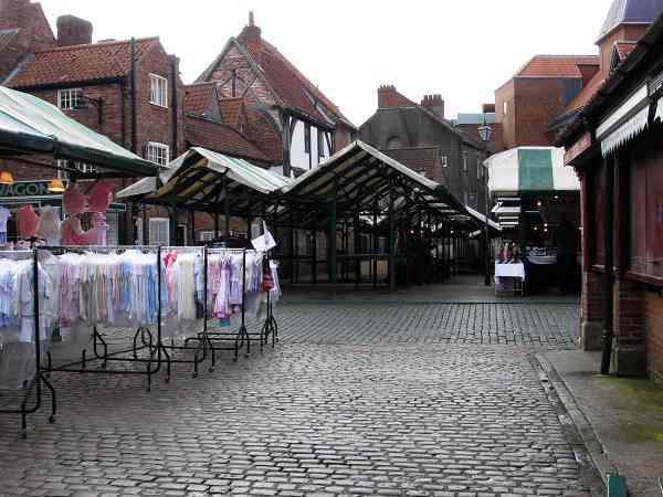 Little Shambles crossing the market in front, with the bulk of the market to the south of it.